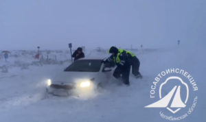 Сотрудники ГИБДД помогают автомобилисту, попавшему в снежный плен